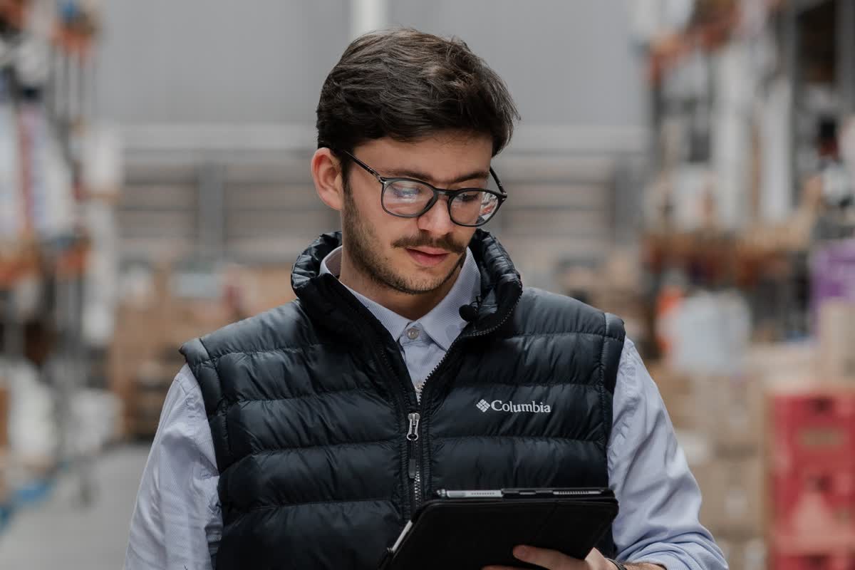 A person in a warehouse holding a tablet, with shelving visible behind: an illustrative image for back-office and inventory work.