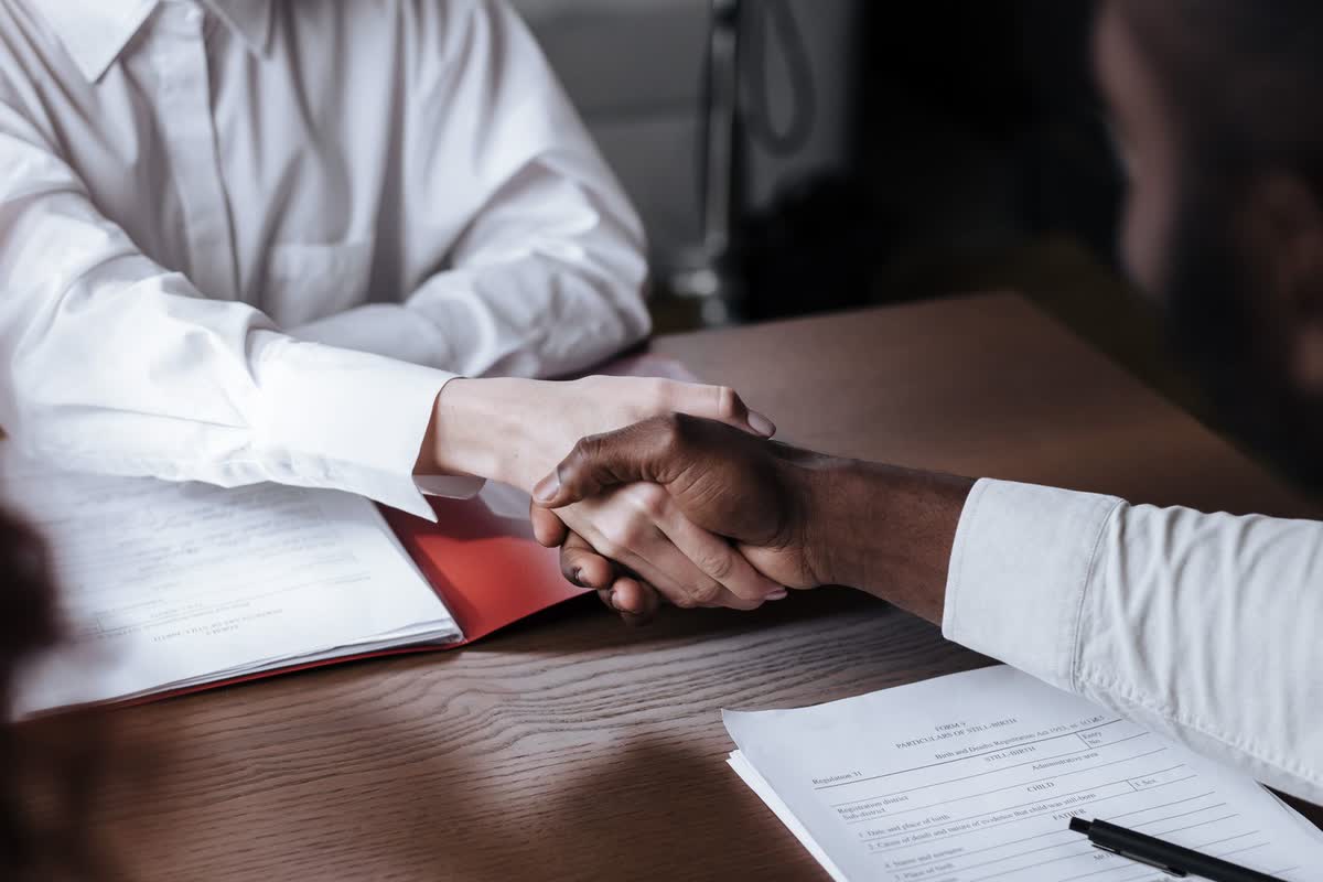 Two unrecognizable hands shaking over a table: an illustrative image for closing an advisory deal.