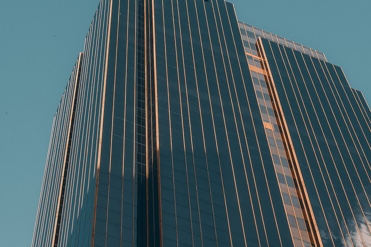 A low-angle view of a modern glass office tower: an illustrative image for financial institutions.