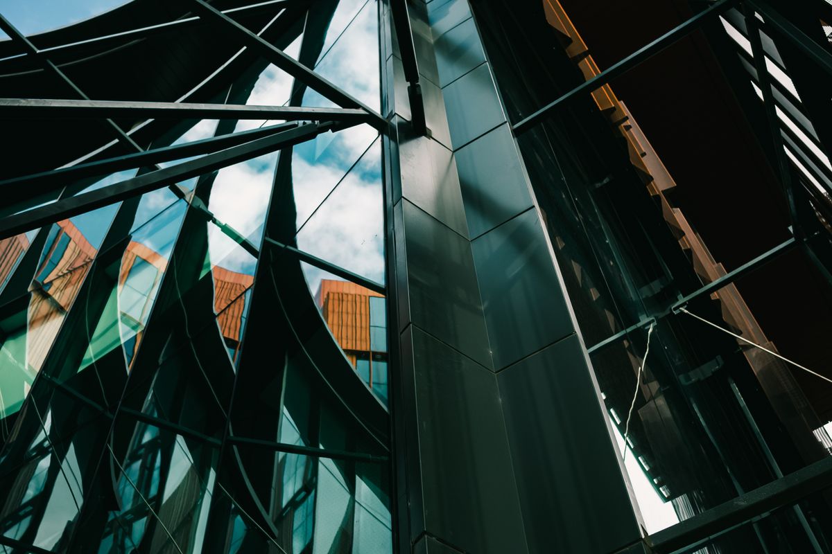 A modern glass tower angled upward with layered reflections — an illustrative image for growth and momentum.