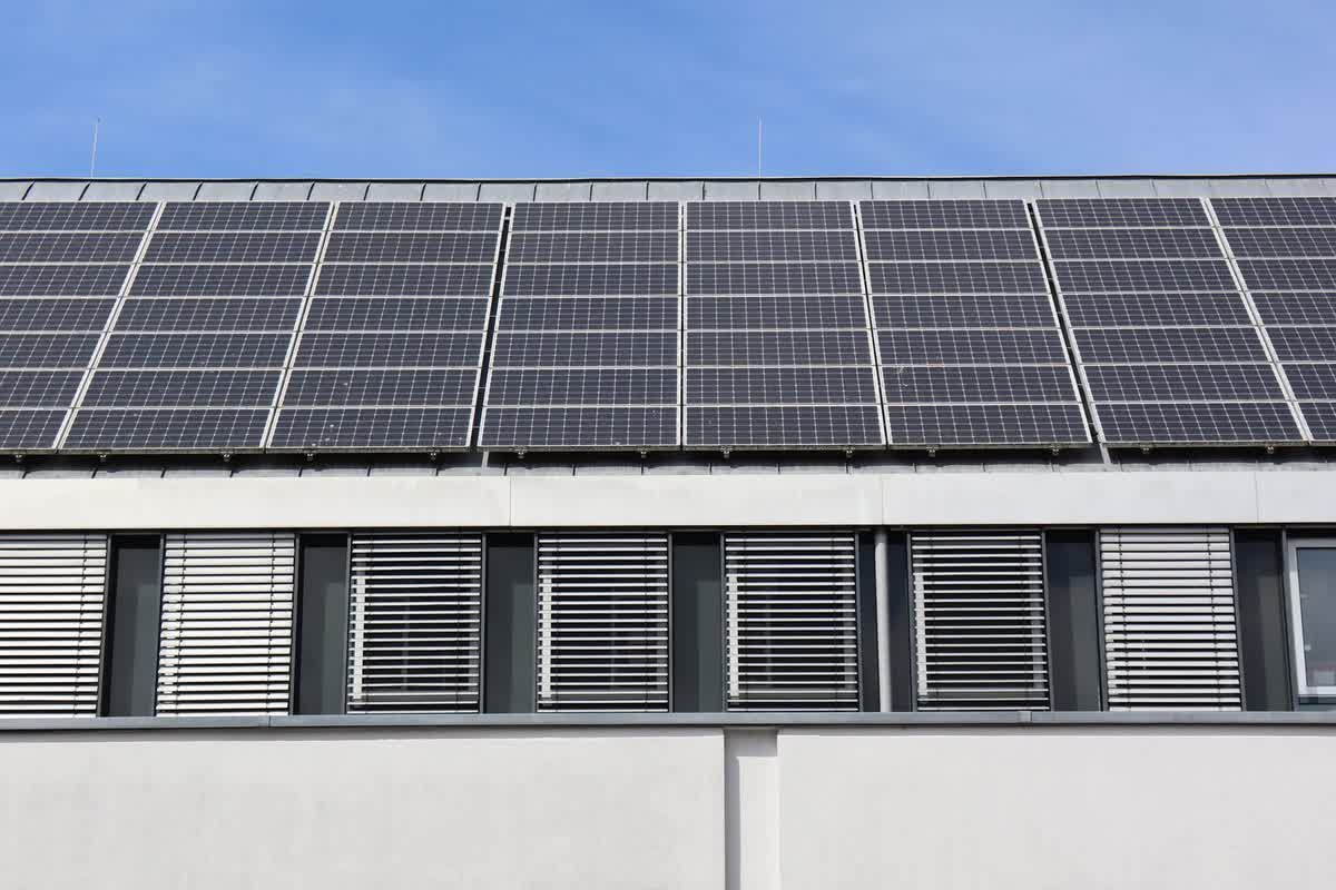 A modern building topped with solar panels under a clear sky: an illustrative image for purpose and sustainability.