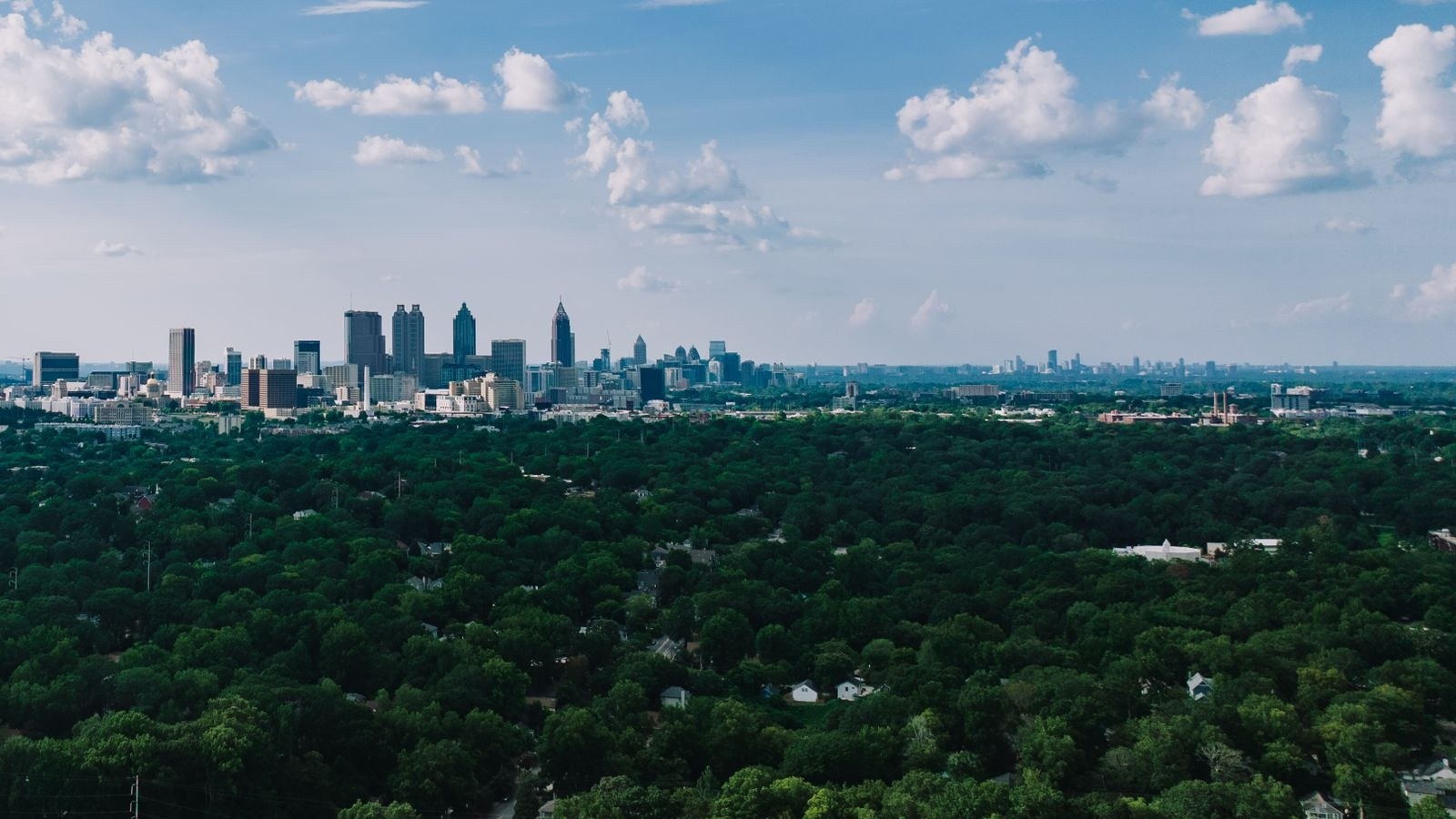 The downtown and Midtown Atlanta skyline rising above the city's tree canopy, illustrative of the Atlanta area.