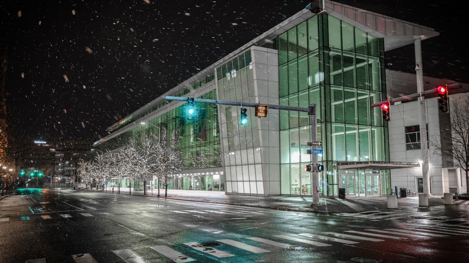 A glass academic building on a snowy night street corner in downtown Stamford, an illustrative image for the firm's Stamford service area.