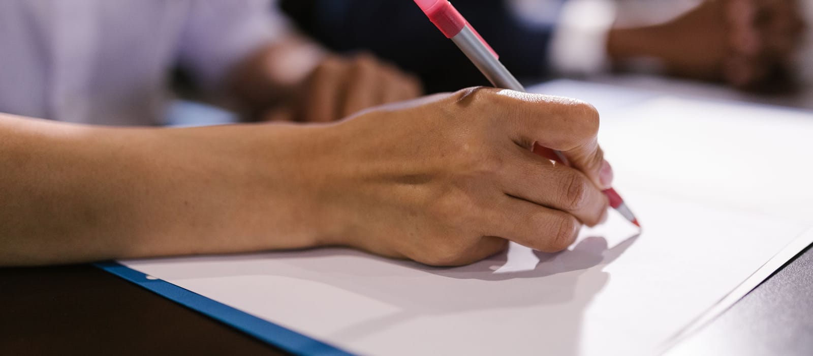 A hand marking up a document across a meeting table, a second reader out of focus: illustrative of how an engagement runs.