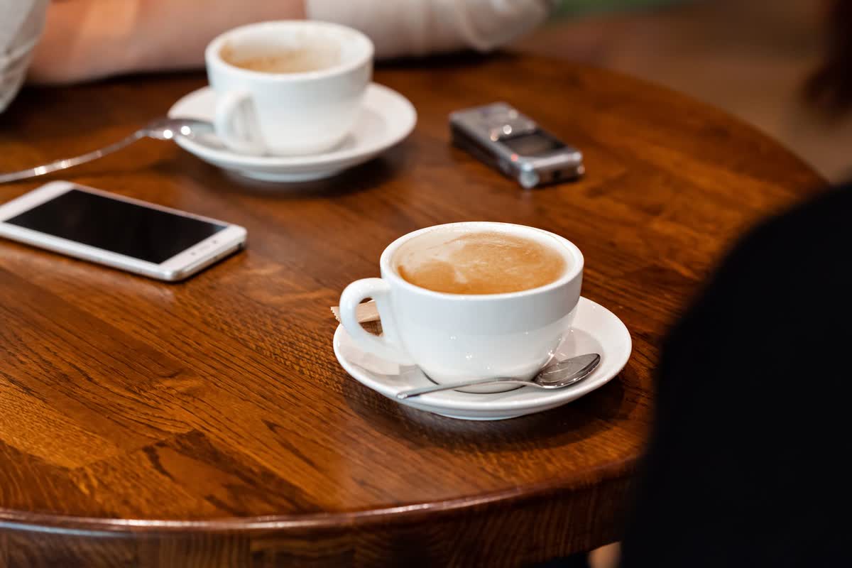Coffee cups and a voice recorder on a table before a conversation, an illustrative image for questions asked plainly.