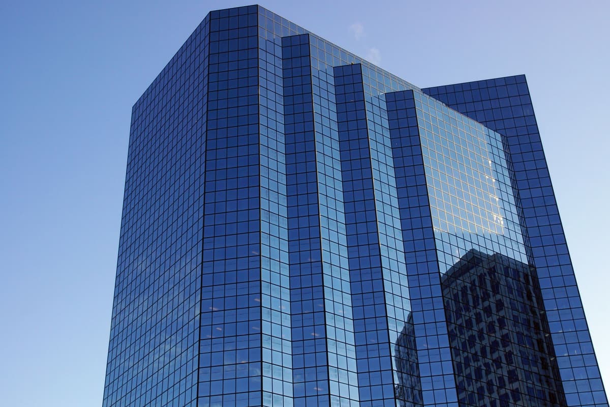 A modern glass office tower against a clear sky: an illustrative image for financial institutions.