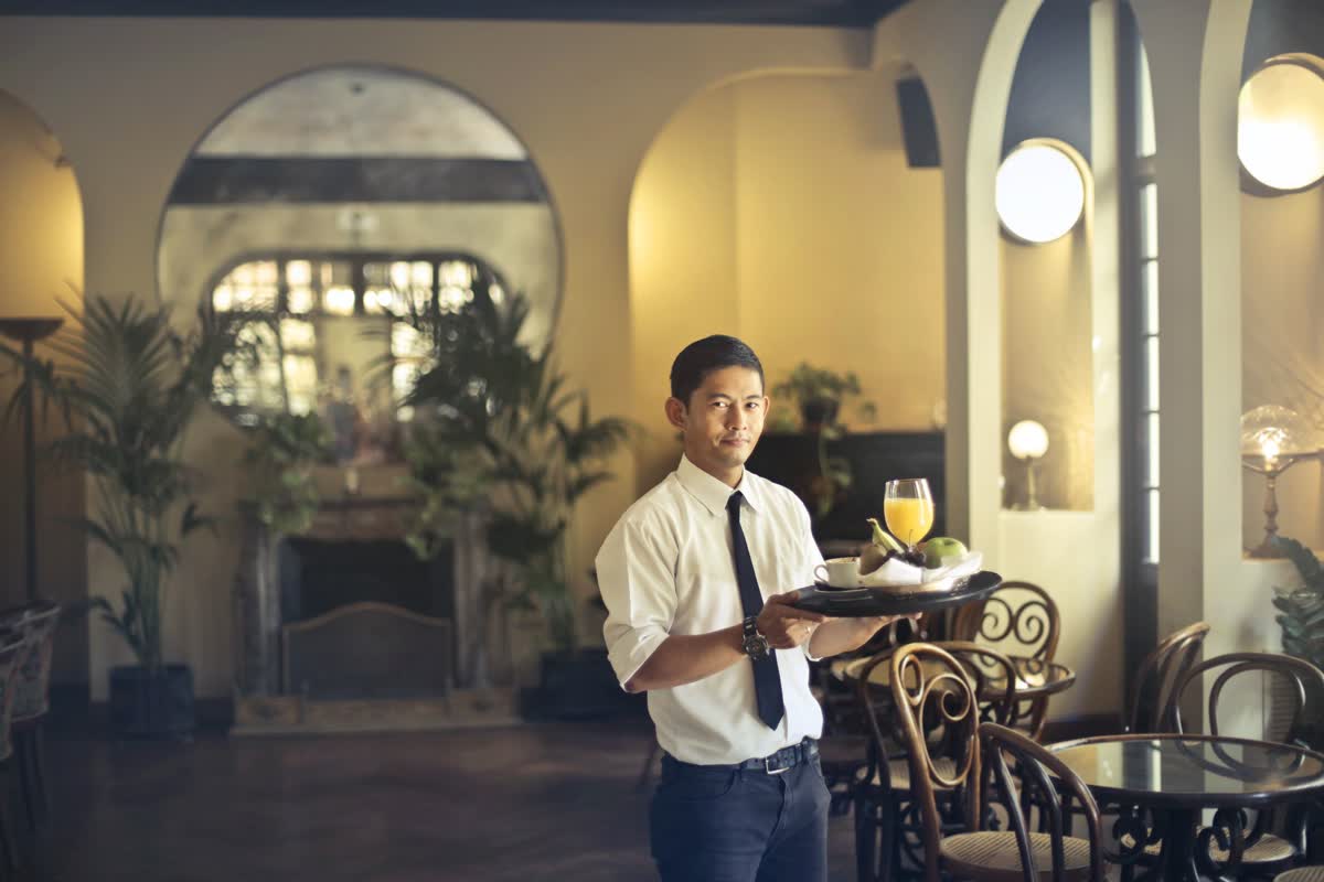 A person carrying a tray of drinks in an ornate restaurant interior: an illustrative image for hospitality and entertainment.