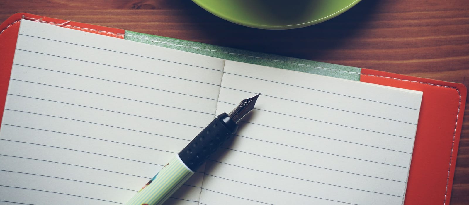 A fountain pen resting on an open, unwritten notebook beside a cup of coffee: an illustrative image for notes from the practice.