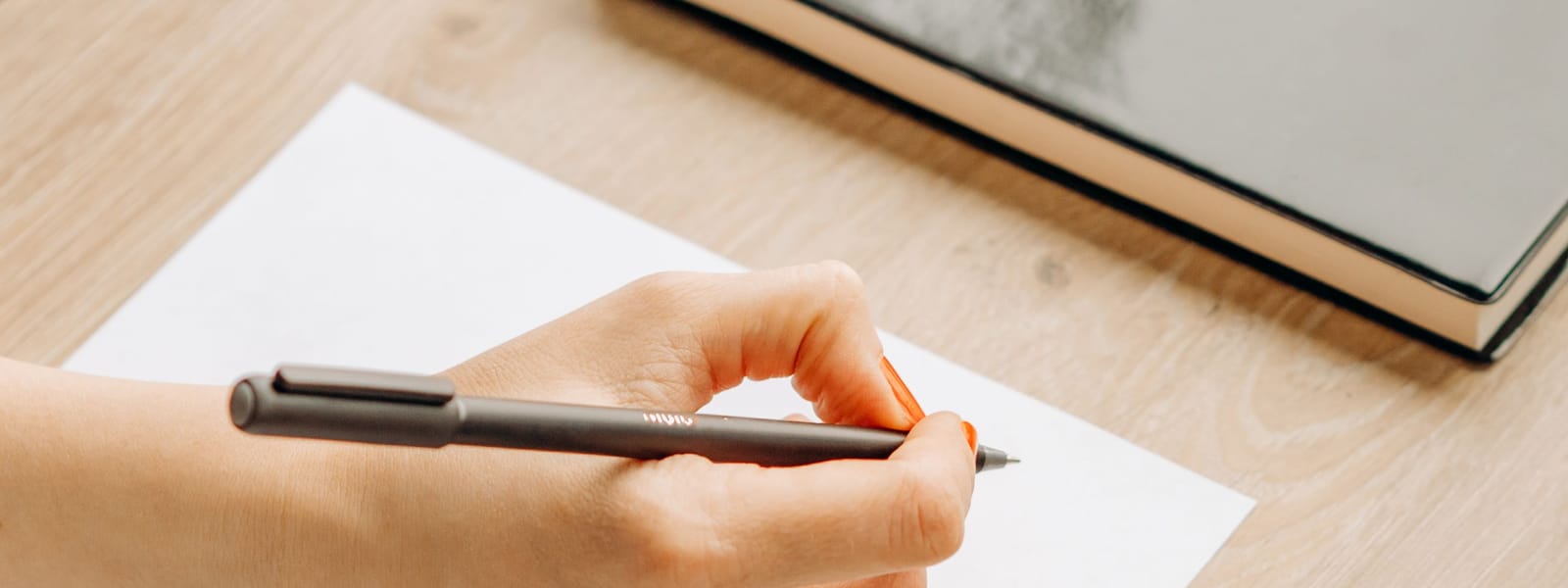 Hands with a pen over a blank sheet on an oak desk: an illustrative image for checking a figure against the document it is credited to.